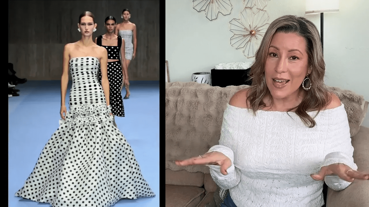 2025 Fashion Forecast: The Trends You’ll Be Obsessed With All Year 13 A woman in an off-shoulder sweater sits on a sofa, gesturing animatedly. On the left, a runway with models in polka dot dresses. The setting is a modern, stylish room with wall decor.